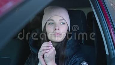 女人在树林里的车里暖手。 冬季寒冷概念